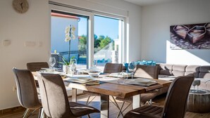Un comedor moderno con una mesa de madera, varias sillas y vistas al exterior a través de amplios ventanales.