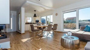 Un salón amplio con mesa de comedor, sillas, sofá y un gran ventanal con vistas al exterior.