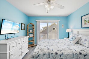 Une chambre à coucher avec un lit, une commode, une télévision et une vue sur l’extérieur.