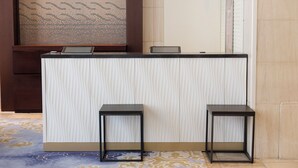A reception desk with two black stools, a patterned wall, and a tiled floor. - JR KYUSHU HOTEL Blossom Fukuoka (Fukuoka)