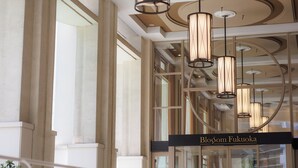 A modern interior with a glass facade, a sign reading "Blossom Fukuoka," and a series of cylindrical pendant lights. - JR KYUSHU HOTEL Blossom Fukuoka (Fukuoka)