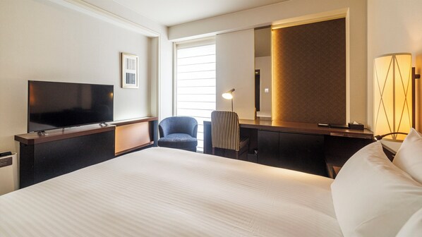 A hotel room with a large bed, a flat-screen TV, a desk with a chair, a lamp, and a large mirror. - JR KYUSHU HOTEL Blossom Fukuoka (Fukuoka)