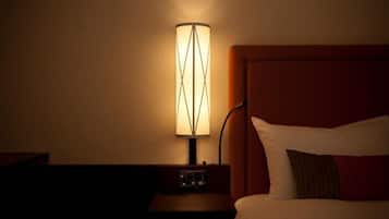 A hotel room with a bed, a nightstand, and a lamp.
