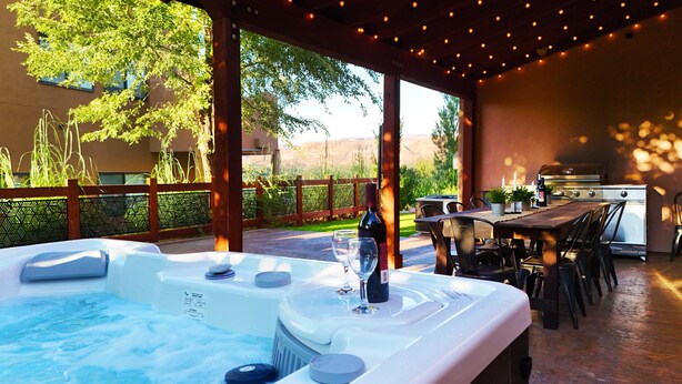 An outdoor hot tub area with a table and chairs, a grill, and a view of the surrounding landscape. - Canyon & Sky: Hot Tub Sanctuary, Redrock Patio Lounge, & Sunset Deck Views! SG2 (Moab)