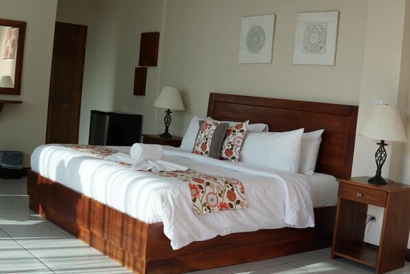 Relax in a spacious room with a large bed, two bedside tables, and a mounted television.