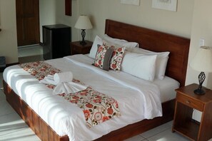 Relax in a spacious room with a large bed, a bedside table, and a stylish lamp.