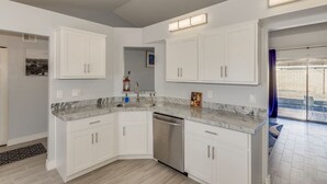 A modern kitchen with white cabinets, a granite countertop, and a built-in dishwasher. - Beautiful remodeled home to enjoy your stay. (Phoenix)
