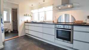 A modern kitchen with a built-in oven, a stainless steel range hood, and a glass backsplash.