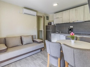 A compact living space with a sofa, a dining table with chairs, a kitchenette, and a small refrigerator. - Mobile home Luxury Premium by Interhome (Pula/Banjole)
