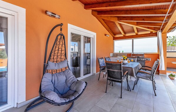A patio area with a hanging chair, dining table, and chairs.