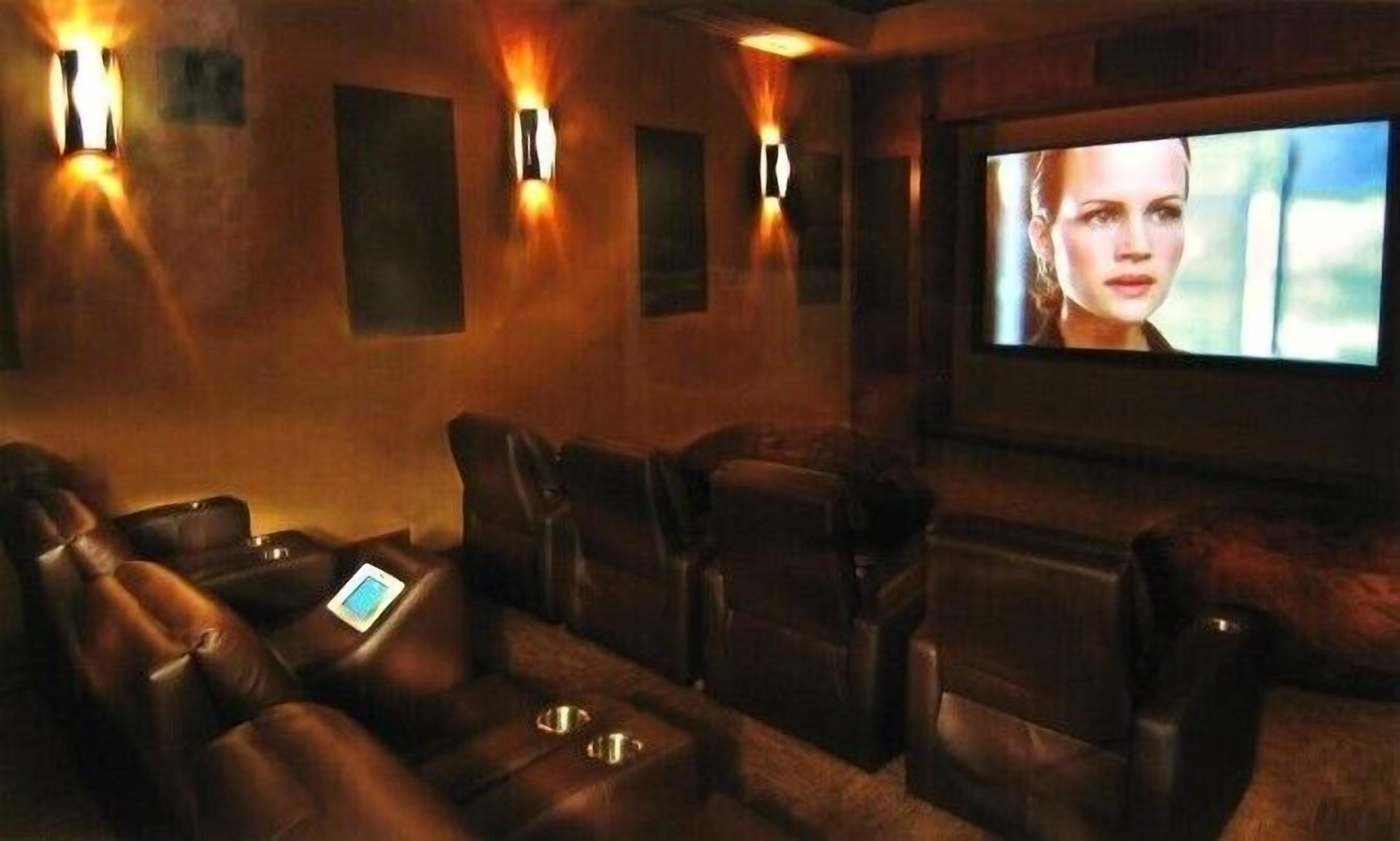 A cinema room with leather reclining seats and a large screen.