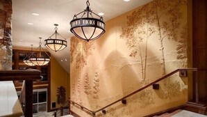 Eine Treppe mit einem Holzgeländer und einer Wand mit einem Baum-Wandbild.