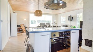 Cozinha moderna com ilha central, forno embutido e luminária pendente.