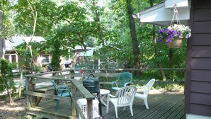 Eine Holzterrasse mit Gartenmöbeln, einem hängenden Blumenkorb und einem Grill.