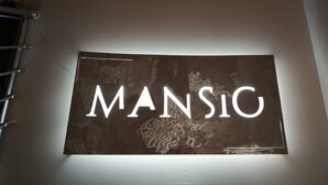 A wall-mounted sign with the word "MANSIC" illuminated in white. - Mansio (Niš)