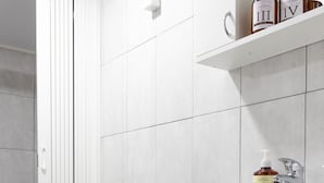 A bathroom with a toilet, a sink, and a shelf with toiletries. - Mansio (Niš)