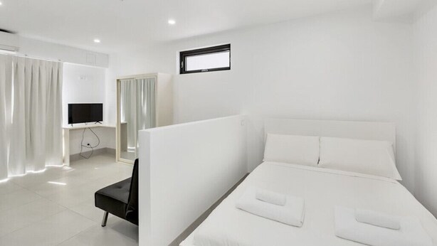 Une chambre d’hôtel moderne avec un grand lit, une télévision et un bureau avec une chaise.