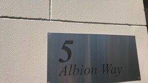 Une plaque métallique portant le numéro 5 et l’inscription « Albion Way », fixée à un mur.