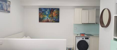 Une petite buanderie équipée d’un lave-linge, de placards et d’un tableau accroché au mur.