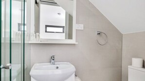 Une salle de bain moderne avec une douche à parois de verre, un lavabo blanc et des toilettes.