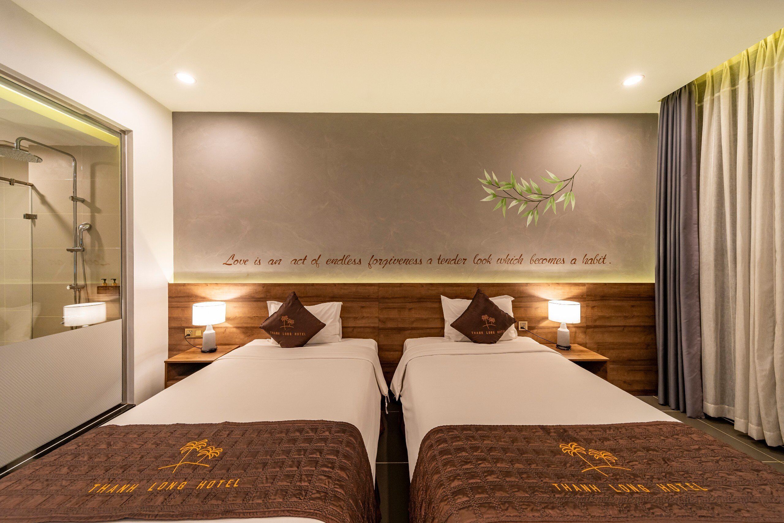 A hotel room with two beds, a shower area, and a decorative wall with a quote.