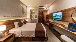 A modern hotel room with a large bed, a desk with a laptop, a television, and a wall-mounted air conditioner. - Thanh Long Hotel Bach Dang (Ho Chi Minh City)