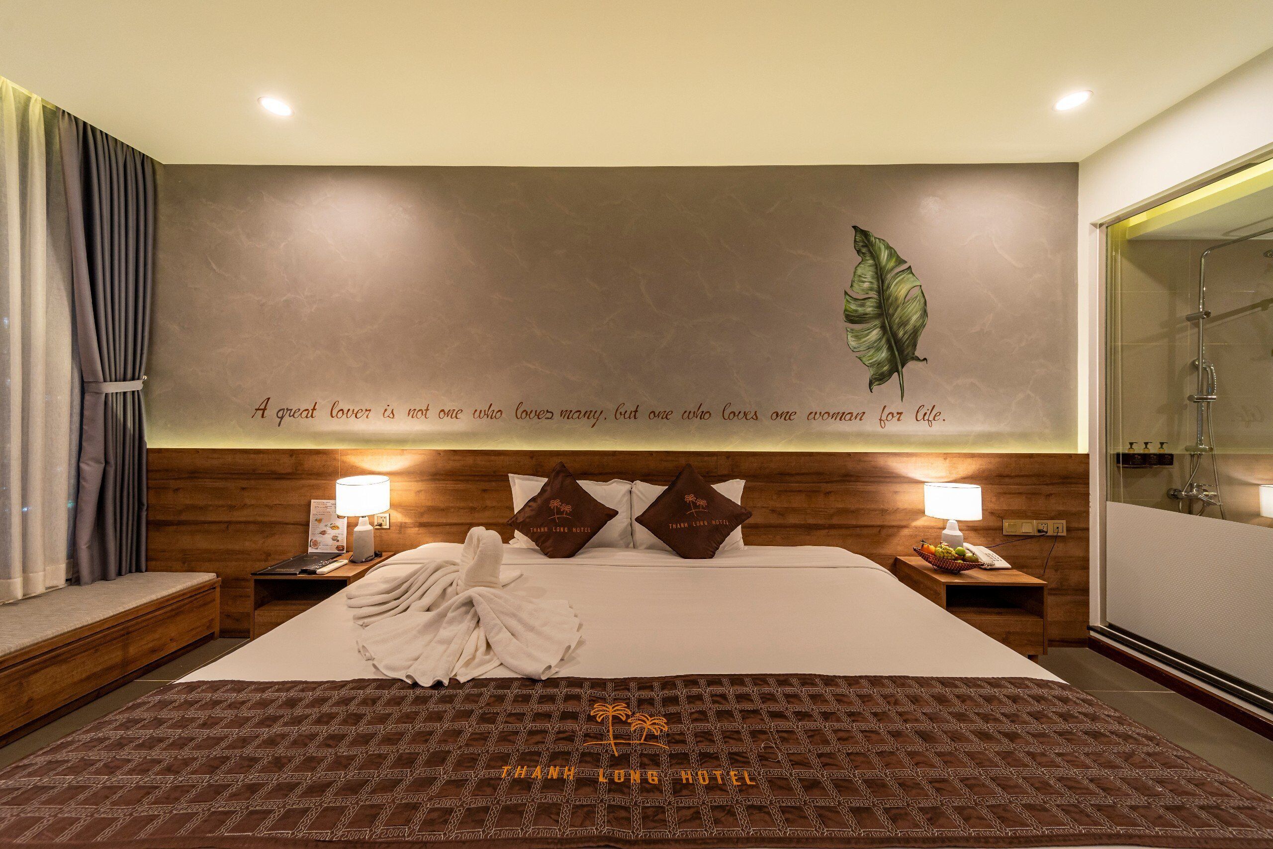 A hotel room with a large bed, wooden headboard, and a wall with a leaf and a quote.