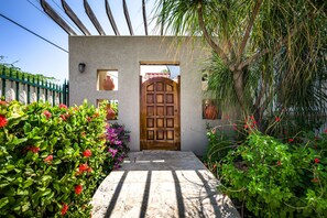 A traditional wooden door with a tiled entrance, surrounded by lush greenery and flowering plants. - Aruban villa in Nord, great view, cozy, safe, short drive to many beaches (Noord)