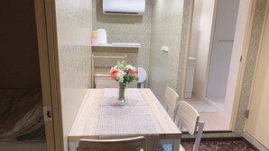 A dining area with a wooden table, chairs, and a vase of flowers. An air conditioner is mounted on the wall above the table. - Hotel Minami (Tokyo)