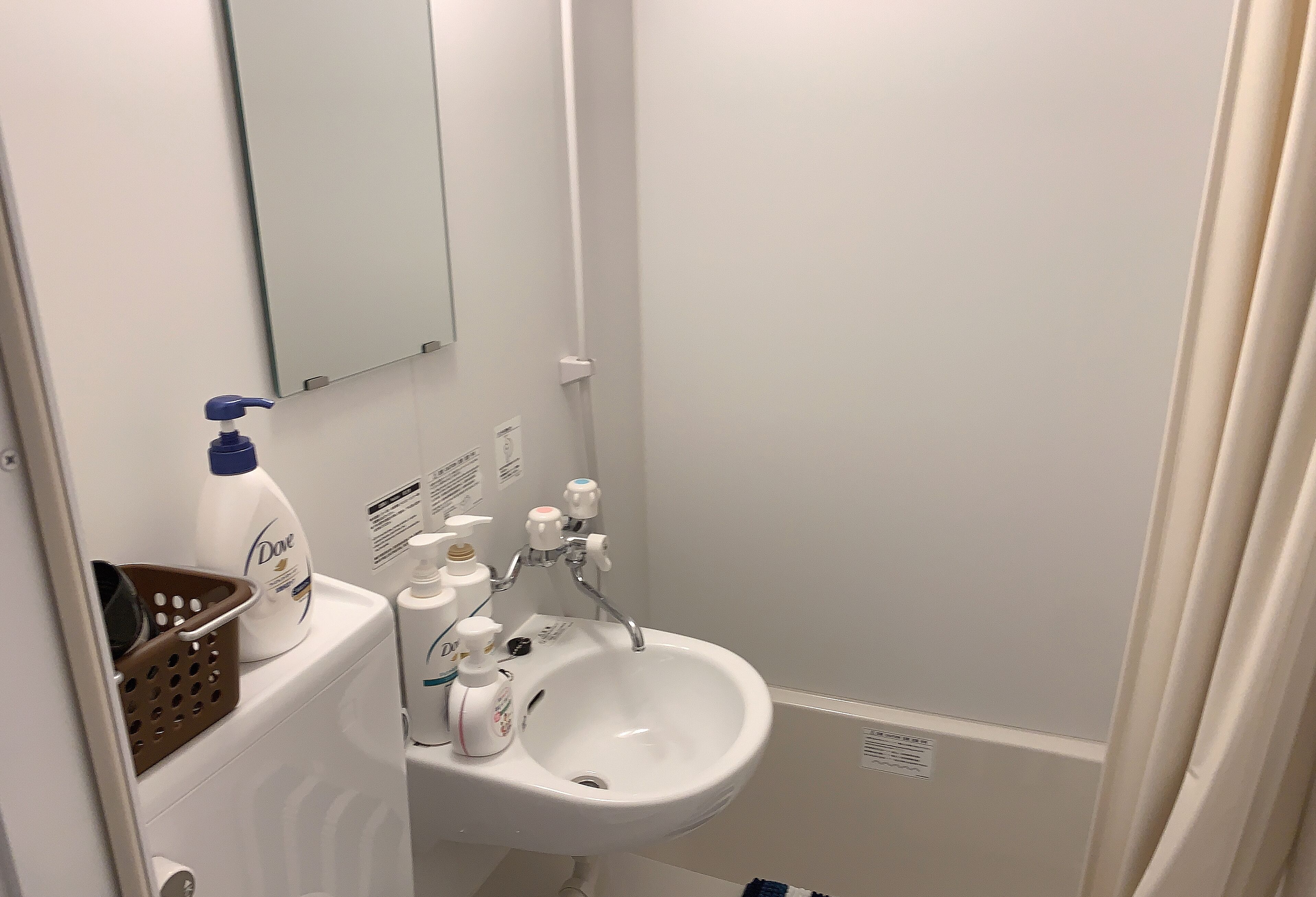 A bathroom with a white sink, a mirror, and toiletries.