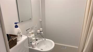 A bathroom with a white sink, a mirror, and toiletries.
