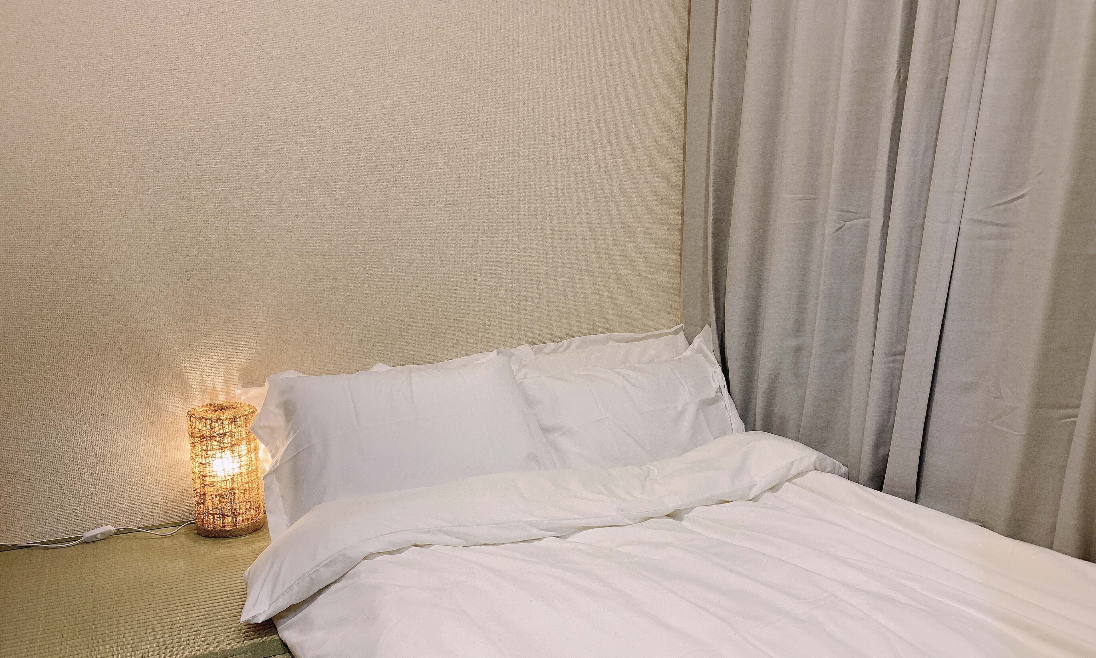 A neatly made bed with white linens in a hotel room.