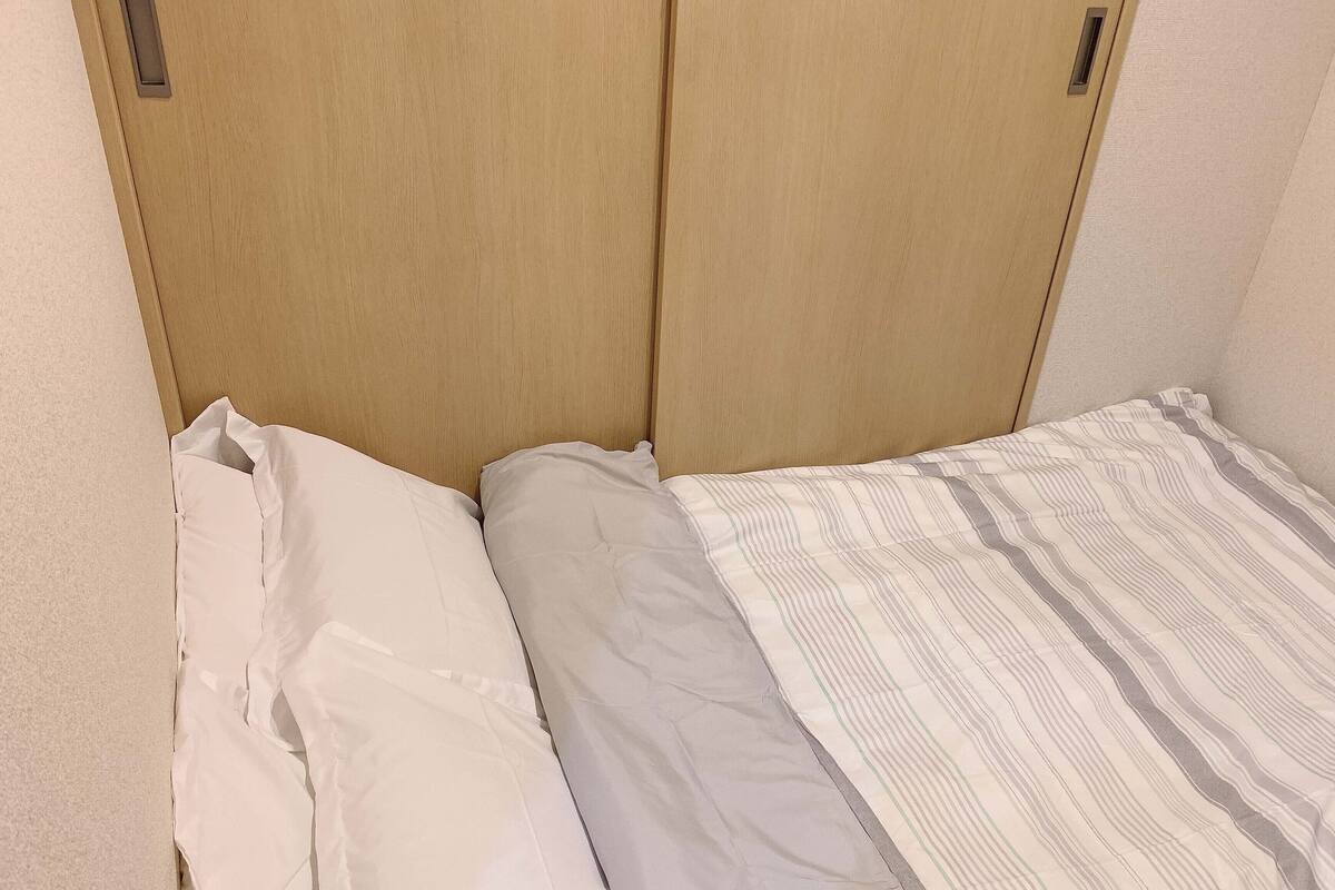 A small, single-bed room with a wooden headboard and a striped bedspread.