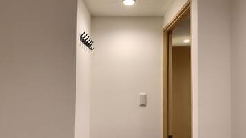 A hallway with a coat rack, a light switch, and a door.