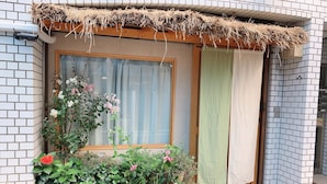 A window with a wooden frame, a mesh screen, and a thatched roof. - Hotel Minami (Tokyo)