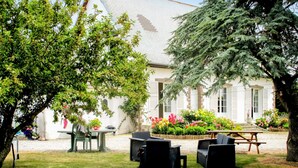 An outdoor seating area with a table and chairs, surrounded by a garden with various plants and flowers. - Awesome home in Surville with WiFi (Surville)