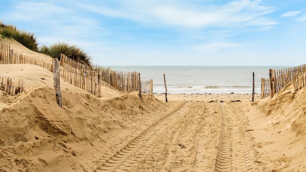 A sandy beach with a wooden fence and tire tracks leading to the water. - Awesome home in Surville with WiFi (Surville)