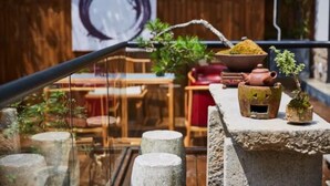 A wooden deck with a stone bench, a small table with a teapot and a plant, and a wooden wall with a circular design. - Floral Hotel Joyful Garden Hangzhou (Hangzhou)