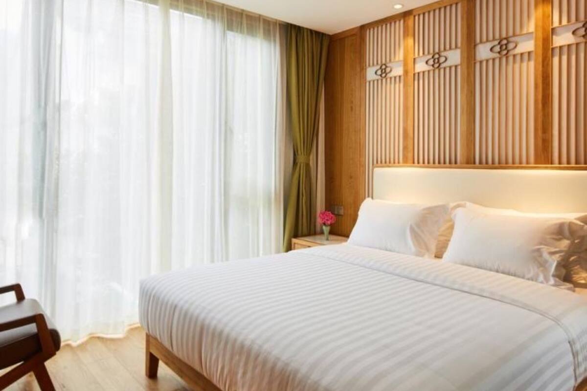A neatly arranged bedroom with a large bed, wooden headboard, and a nightstand with a vase of flowers.