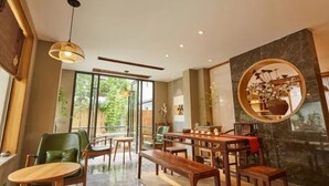 A modern dining area with wooden furniture, a large mirror, and a view of greenery outside. - Floral Hotel Joyful Garden Hangzhou (Hangzhou)