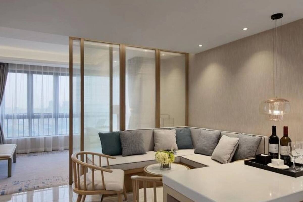 Ein modernes Wohnzimmer mit einem Ecksofa, einem kleinen runden Tisch und einer Bar, komplett mit Gläsern und Flaschen.