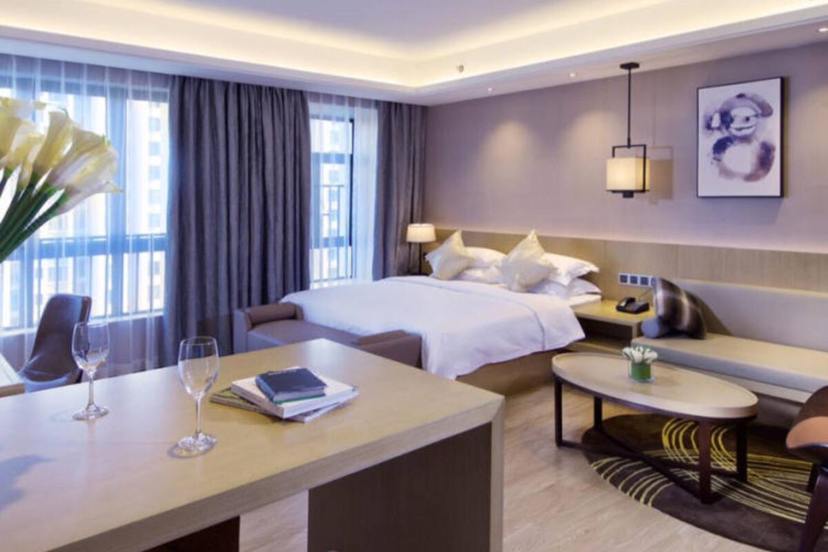 Ein Hotelzimmer mit Bett, Sofa, Esstisch mit Stühlen, einem kleinen runden Tisch und einem Nachttisch.