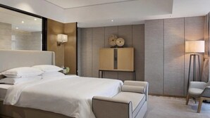 A modern hotel room with a large bed, a bedside table, a chair, and a mirror. - Oriental Ginza International Hotel (Dongguan)