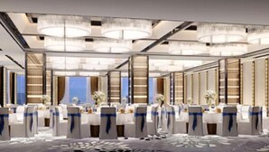 A modern hotel conference room with rows of tables, blue sashes, and chandeliers. - Oriental Ginza International Hotel (Dongguan)