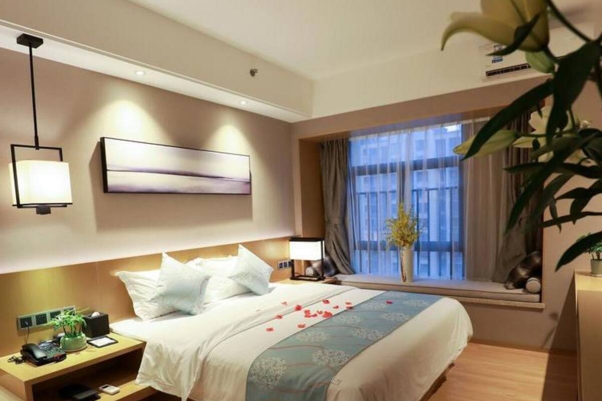 Ein modernes Hotelzimmer mit einem großen Bett, Nachttischen, einem Schreibtisch und einem Fenster mit Vorhängen.