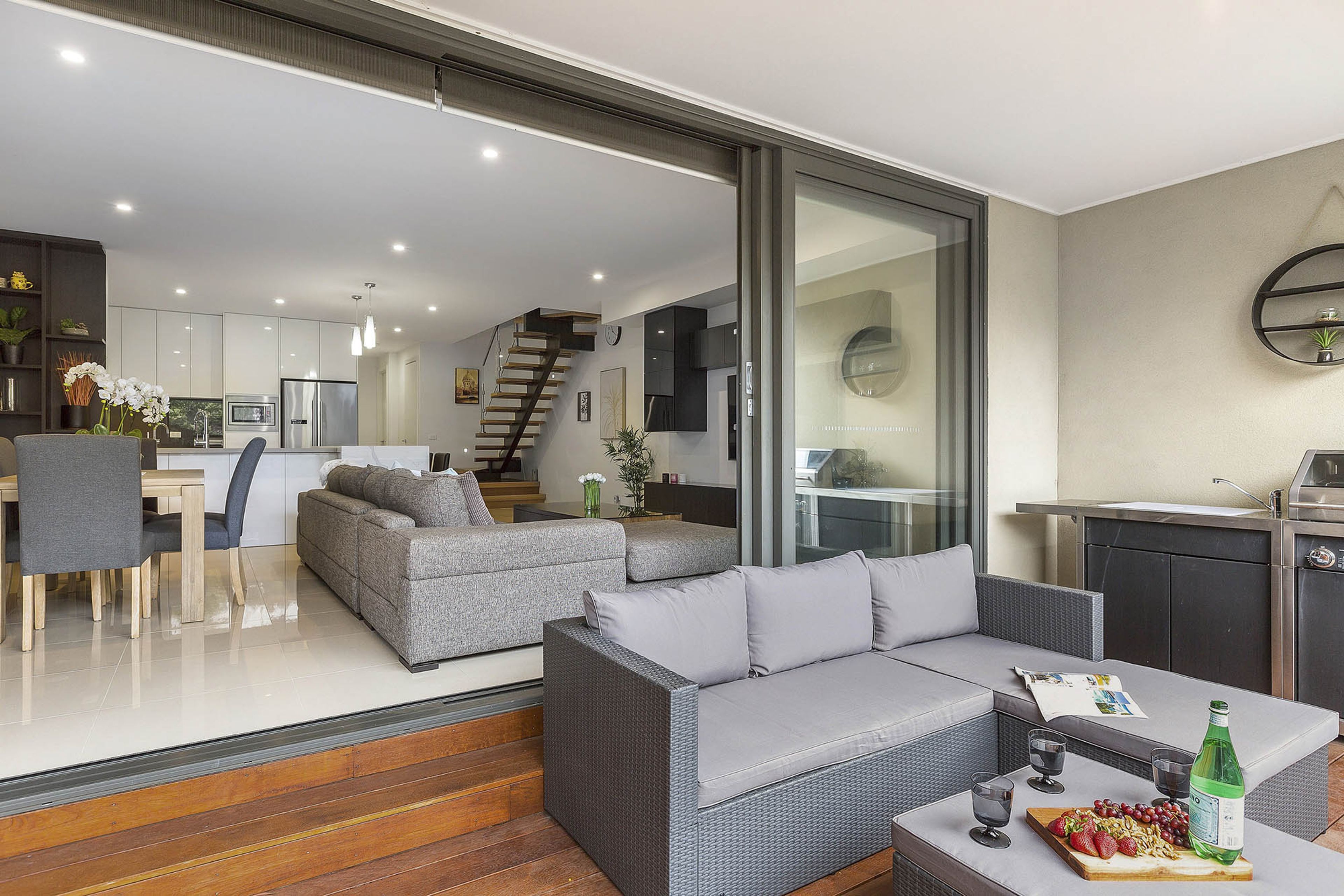 A modern living area with a sofa, dining table, and kitchen in the background.