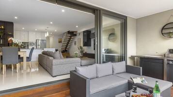 A modern living area with a sofa, dining table, and kitchen in the background.