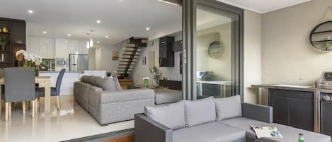 A modern living area with a sofa, dining table, and kitchen in the background.
