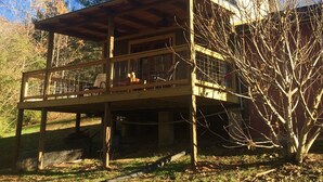 Une cabane en bois dotée d’un balcon, entourée d’arbres et surplombant un ciel bleu azur.