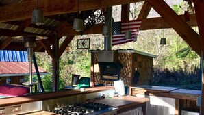 Un espace cuisine extérieur équipé d’une cuisinière à gaz, d’un four et d’un drapeau américain suspendu.
